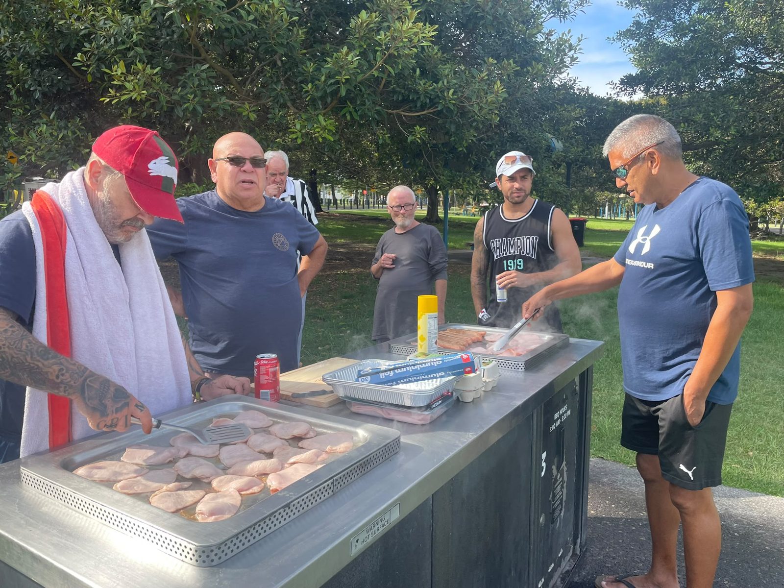 Support workers and participants at a community barbecue in a Sydney park